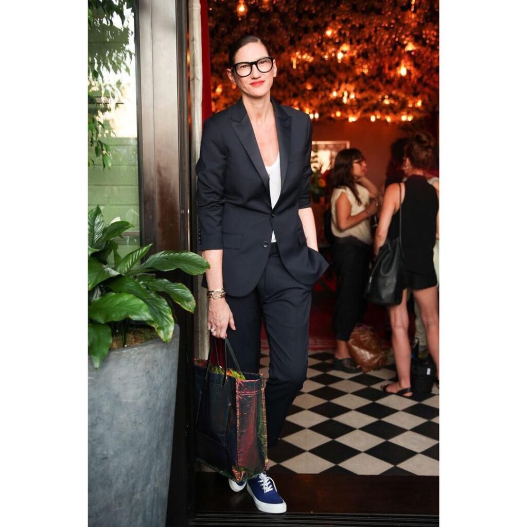 Woman in navy suit with sneakers and tank top – stylish professional outfit with bold accessories