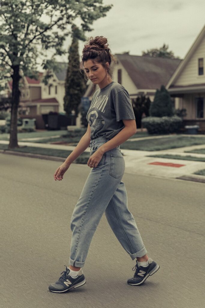 A woman sporting vintage mom jeans paired with a tucked-in graphic tee and retro-styled New Balance sneakers