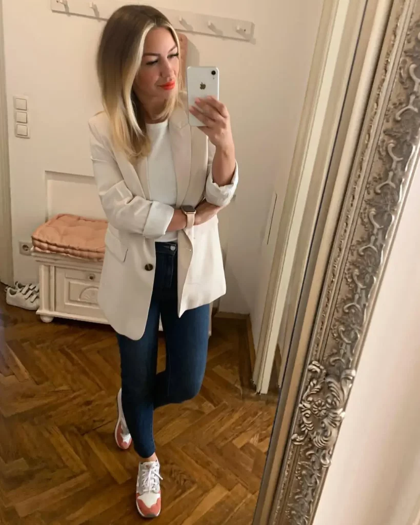 Woman wearing white blazer, skinny jeans, and colorful sneakers – casual business outfit mirror selfie