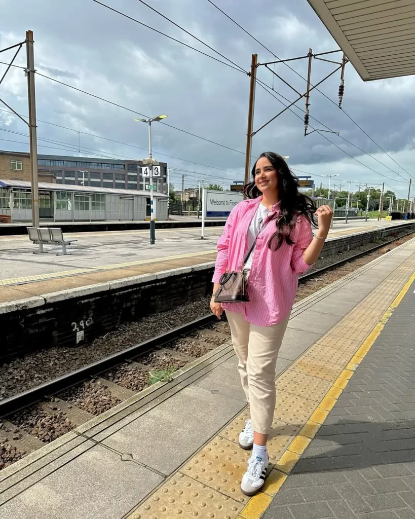 A pink striped oversized shirt adds a fun pop over a basic white tee, while beige tapered pants keep things soft and relaxed