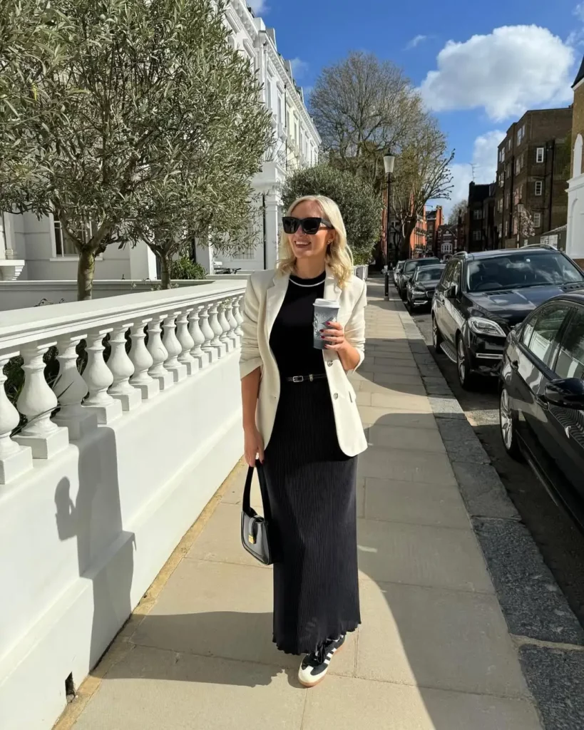 A flowy black maxi dress with fine pleating gives a soft, feminine silhouette, while the belted waist adds sleek definition