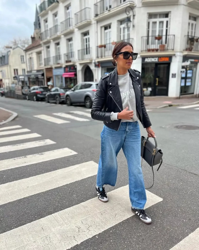 Start with light-wash wide-leg jeans, throw on a heather gray graphic sweatshirt, and layer with a cropped black leather jacket. Then lace up your black Adidas Sambas