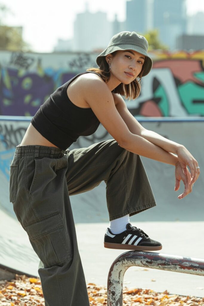 A woman in cargo pants, a black tank, and black Adidas Sambas channels oversized street vibes.