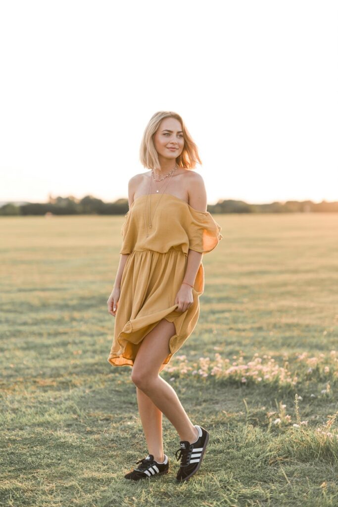 A woman in a mustard dress and black Adidas Sambas channels boho summer festival vibes.