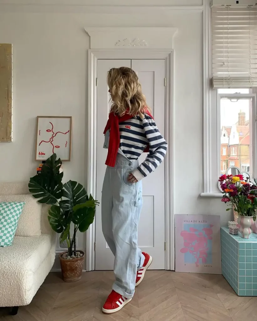 A classic navy and white striped top pairs with slouchy light-wash overalls and bold red Adidas Campus 00s