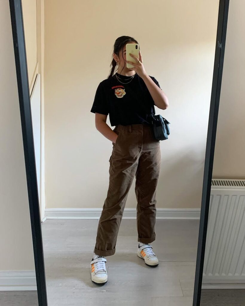 Black graphic tee + chocolate brown corduroy pants + white Adidas Forum Low with orange accents