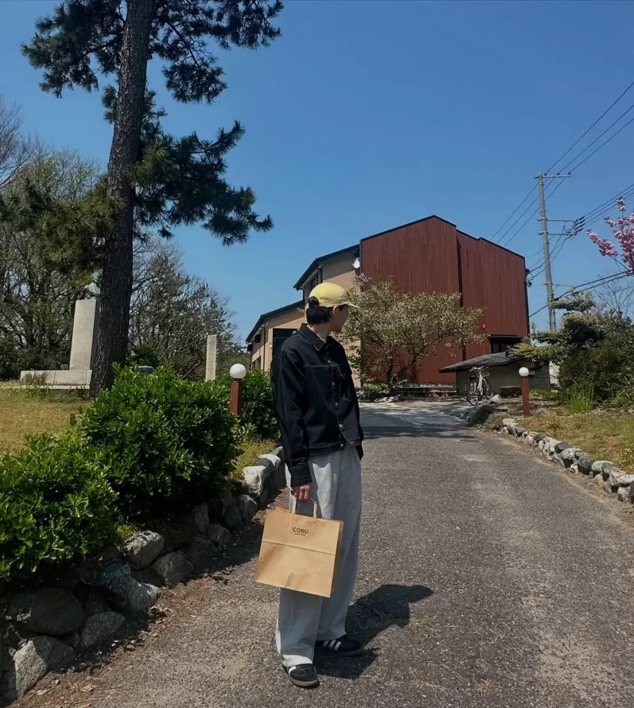 Black Adidas Sambas keep the tone low-key but stylish. A pale yellow cap adds just enough pop to lift the look.