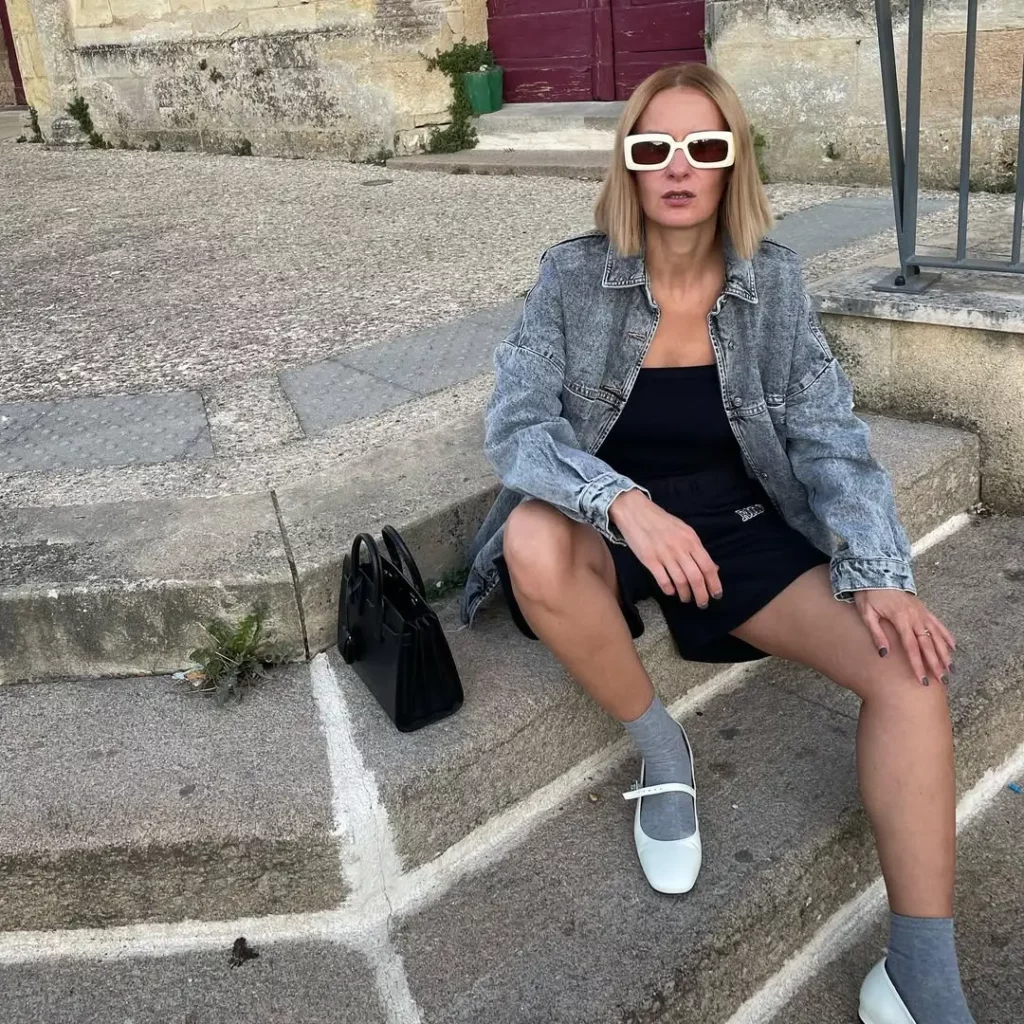 A charcoal denim jacket and black lounge set keep the look chill, but the white Mary Janes with grey socks bring softness and contrast.