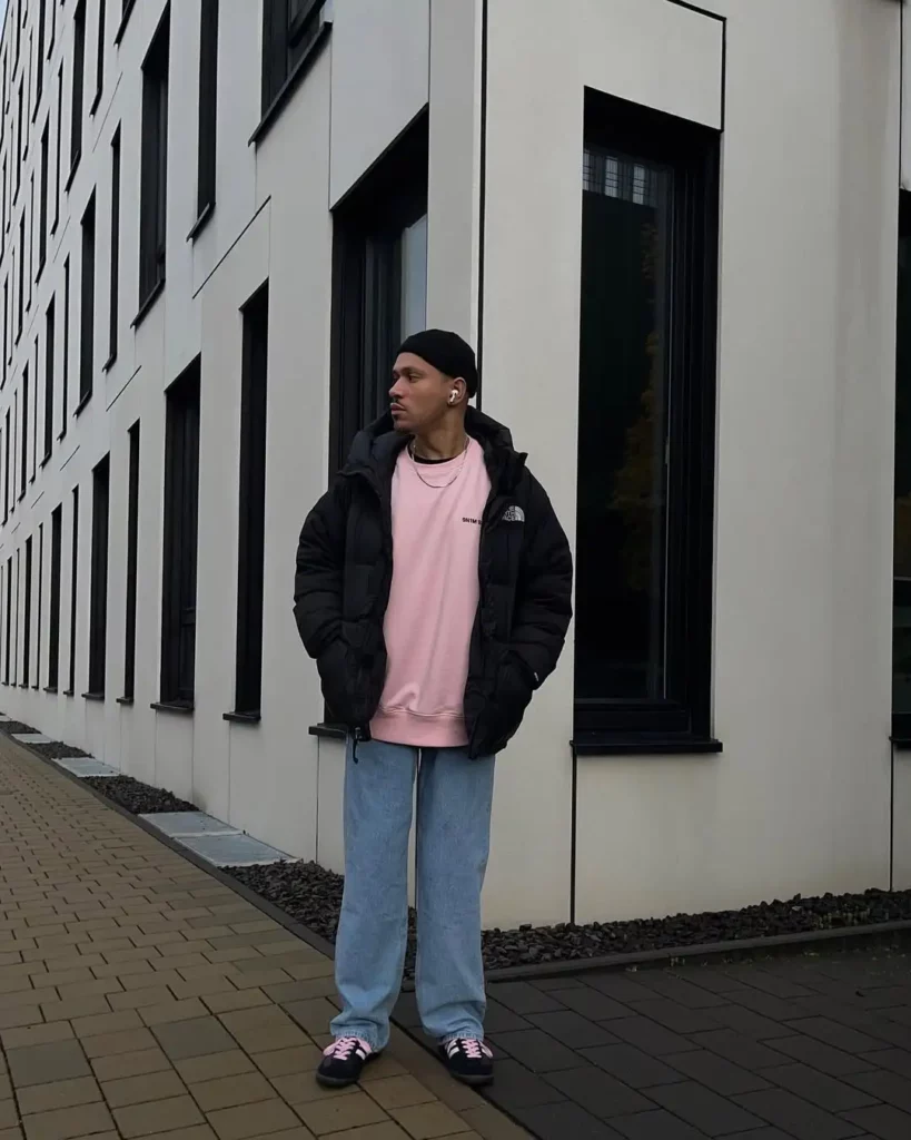 A soft pink oversized tee adds contrast under the bulky black puffer jacket, while light-wash denim brings balance.