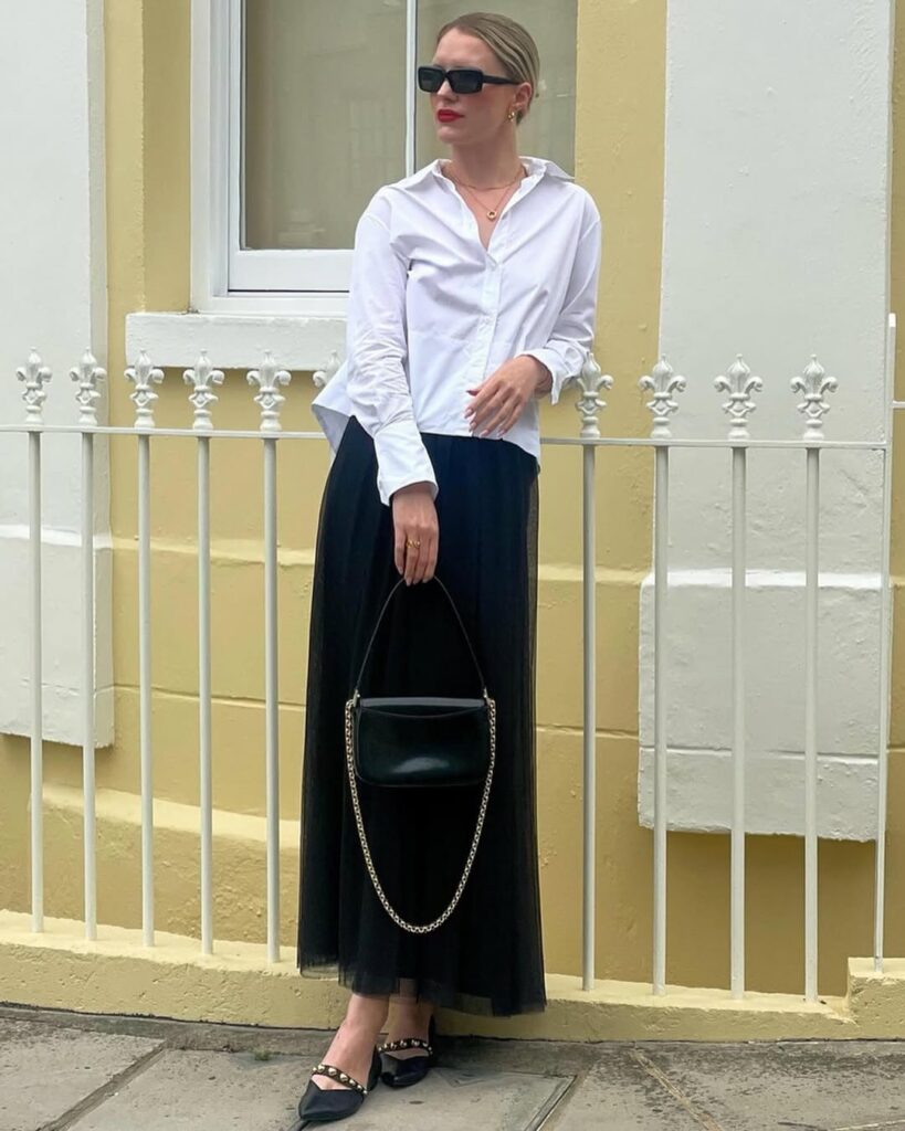 This outfit proves that simple black and white can be anything but boring. A crisp white button-up shirt paired with a flowing black midi skirt sets the foundation for a classic office look.
