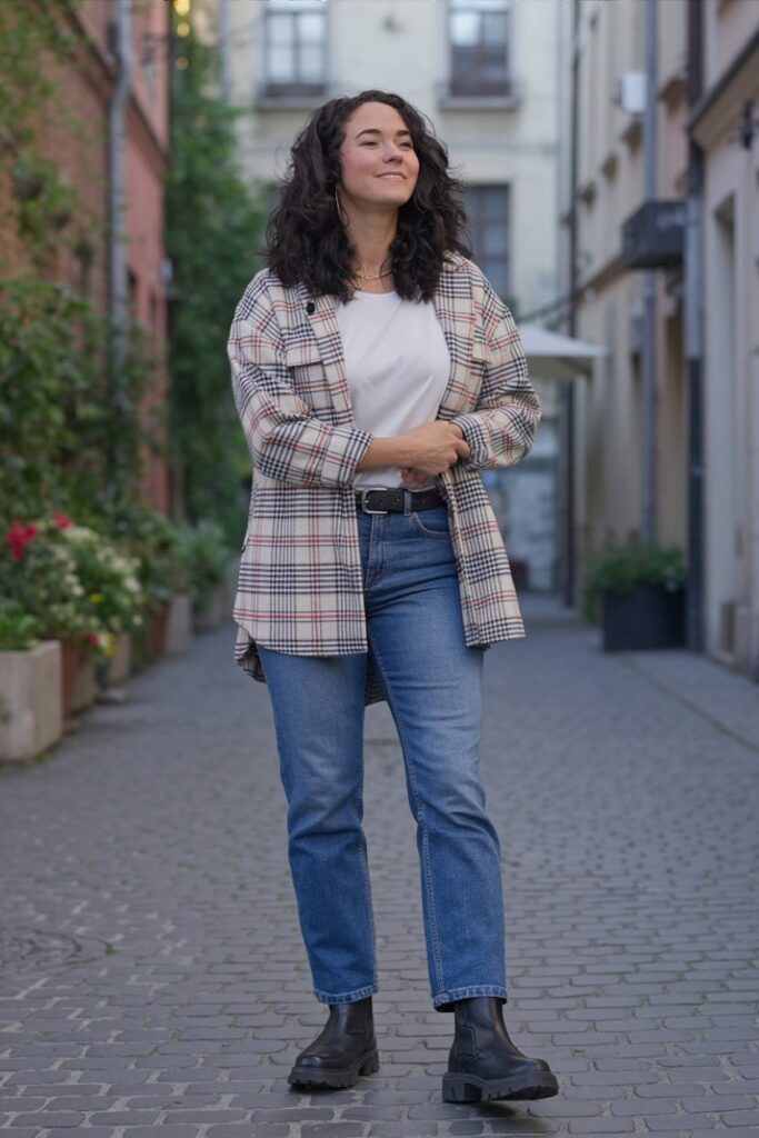 woman wearing plaid shacket over white tee, straight-leg jeans, and chunky lug boots, standing casually, relaxed weekend vibe.
