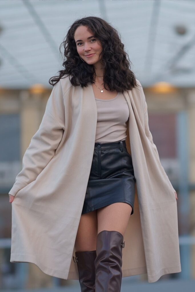woman in oversized cardigan, mini skirt, and knee-high boots, standing naturally, soft layered outfit.